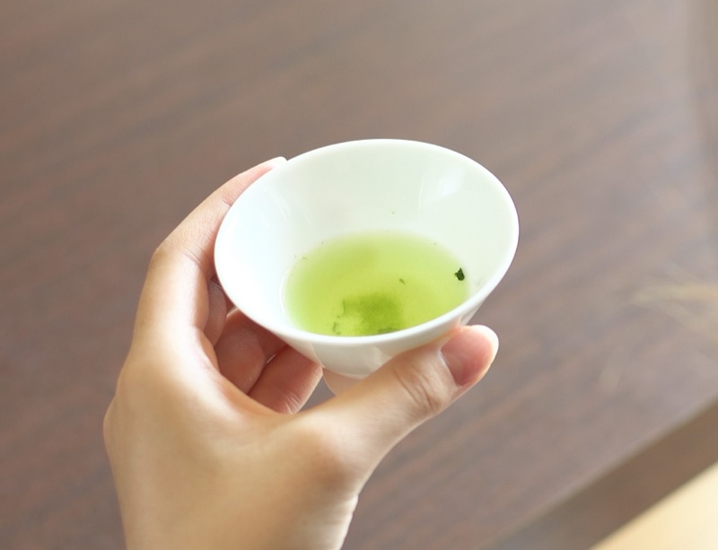Holding a small cup of brewed gyokuro, its deep green liquor catching the light