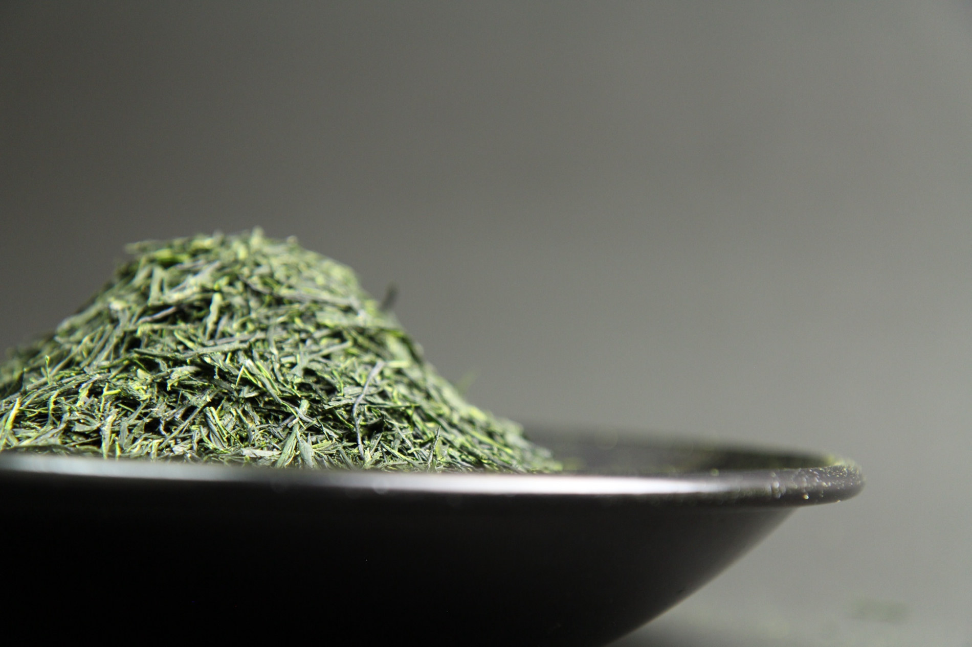 Needle-fine gyokuro leaves piled on a black dish